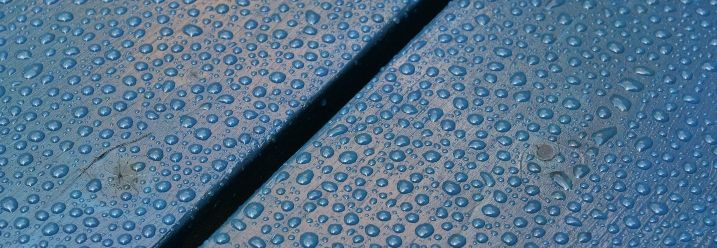 Wasserperlen auf blauer Holzterrasse
